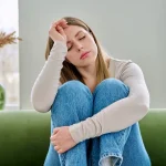 Woman sitting on a couch looking exhausted, representing ADHD burnout and mental fatigue