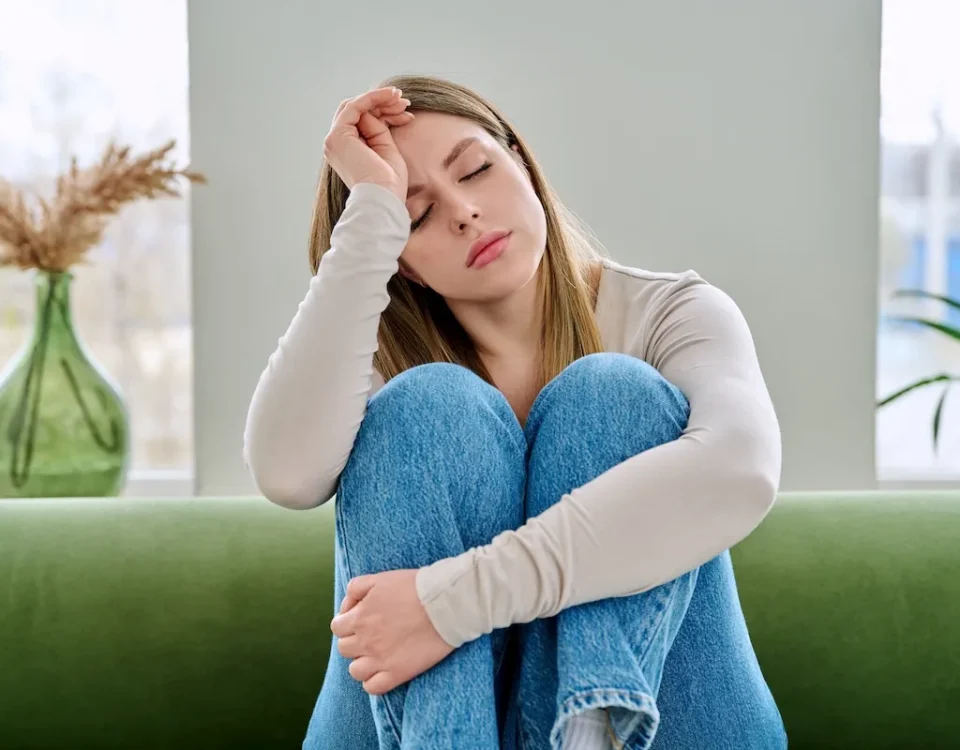 Woman sitting on a couch looking exhausted, representing ADHD burnout and mental fatigue