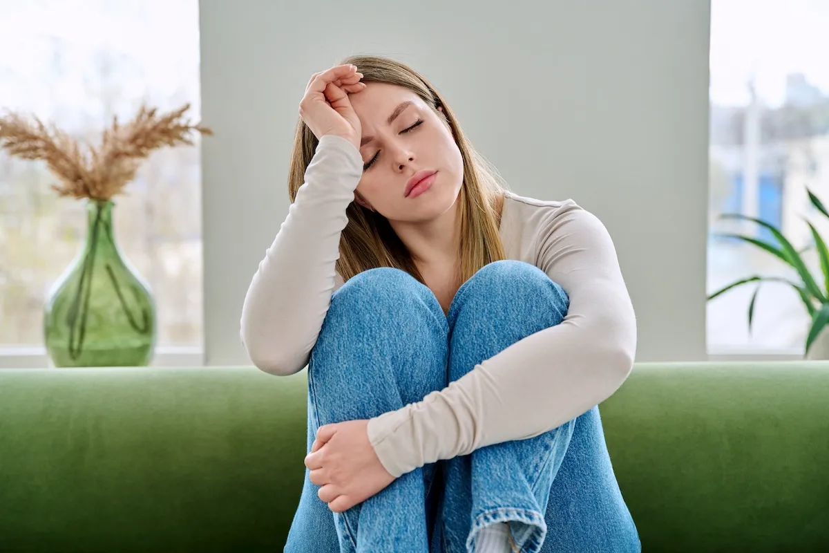 Woman sitting on a couch looking exhausted, representing ADHD burnout and mental fatigue
